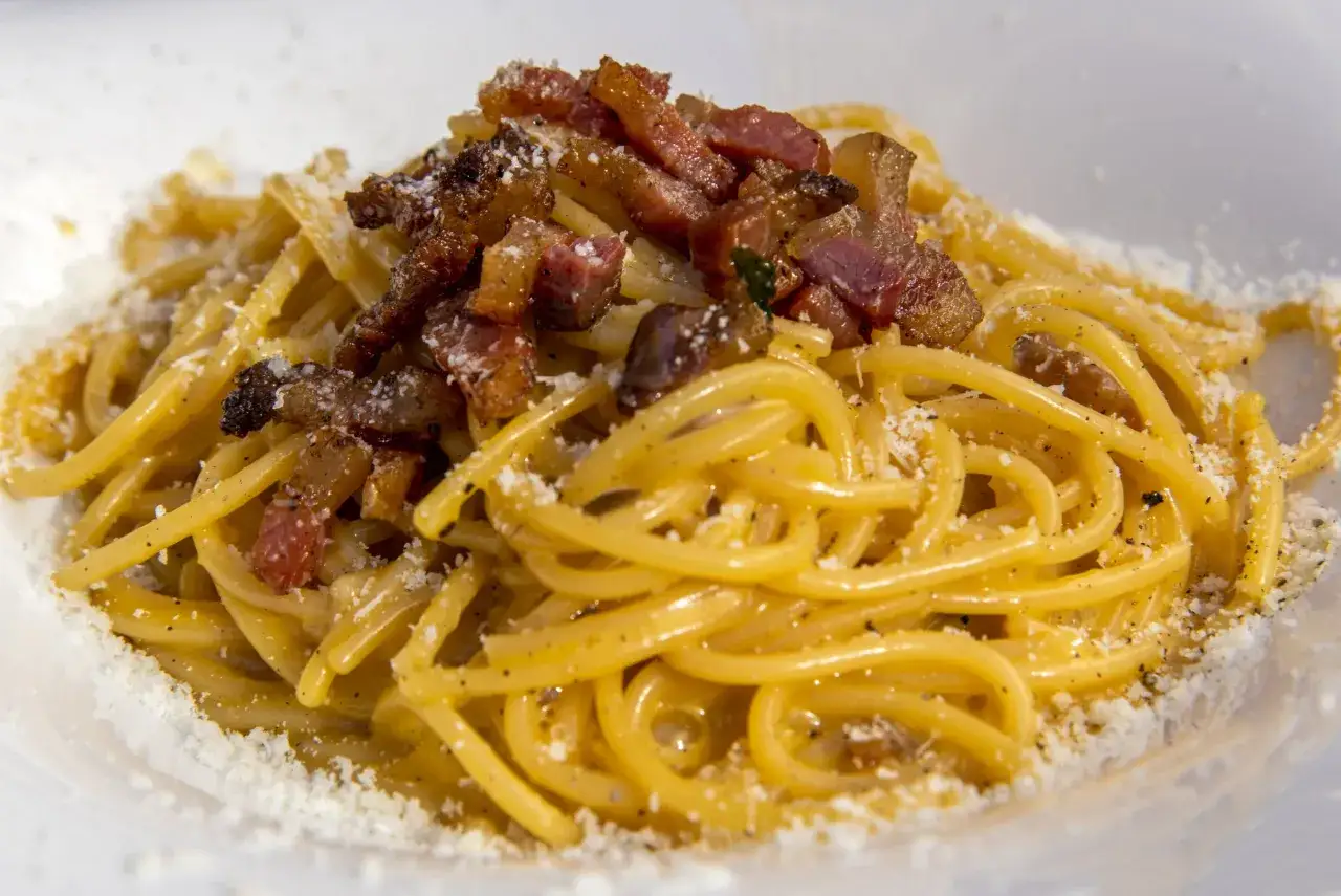 Spaghetti alla carbonara fumanti, guanciale croccante e pecorino. Perfetta con un bicchiere di vino bianco o rosso.