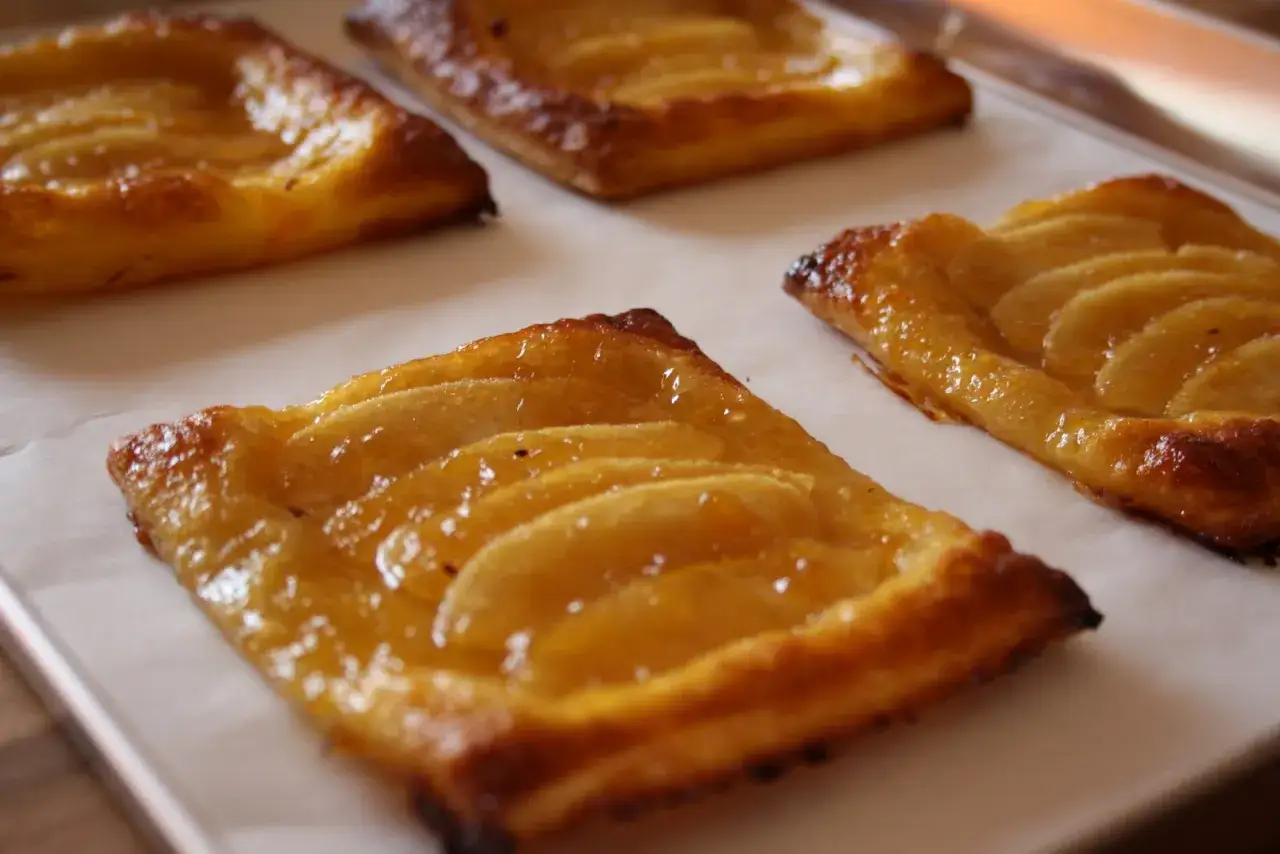 Deliziose tortine di pasta sfoglia con mele caramellate e zucchero di canna, appena sfornate e pronte per essere gustate.