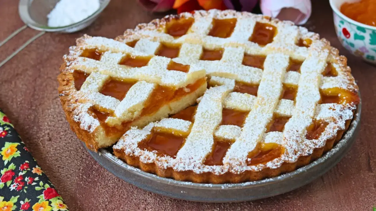 Deliziosa crostata di marmellata con una fetta tagliata, cosparsa di zucchero a velo. Un classico intramontabile per ogni occasione.
