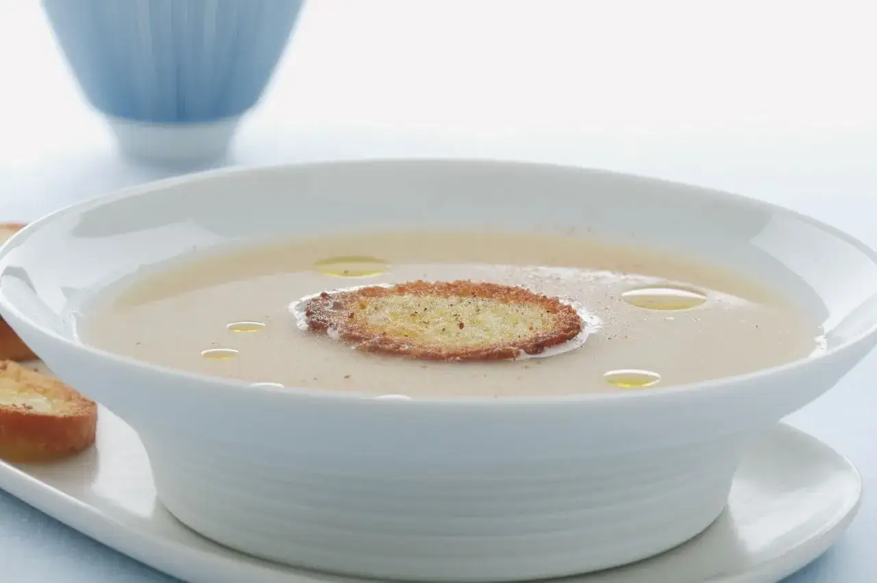 Una vellutata crema di parmigiano, guarnita con crostini dorati e gocce d'olio.