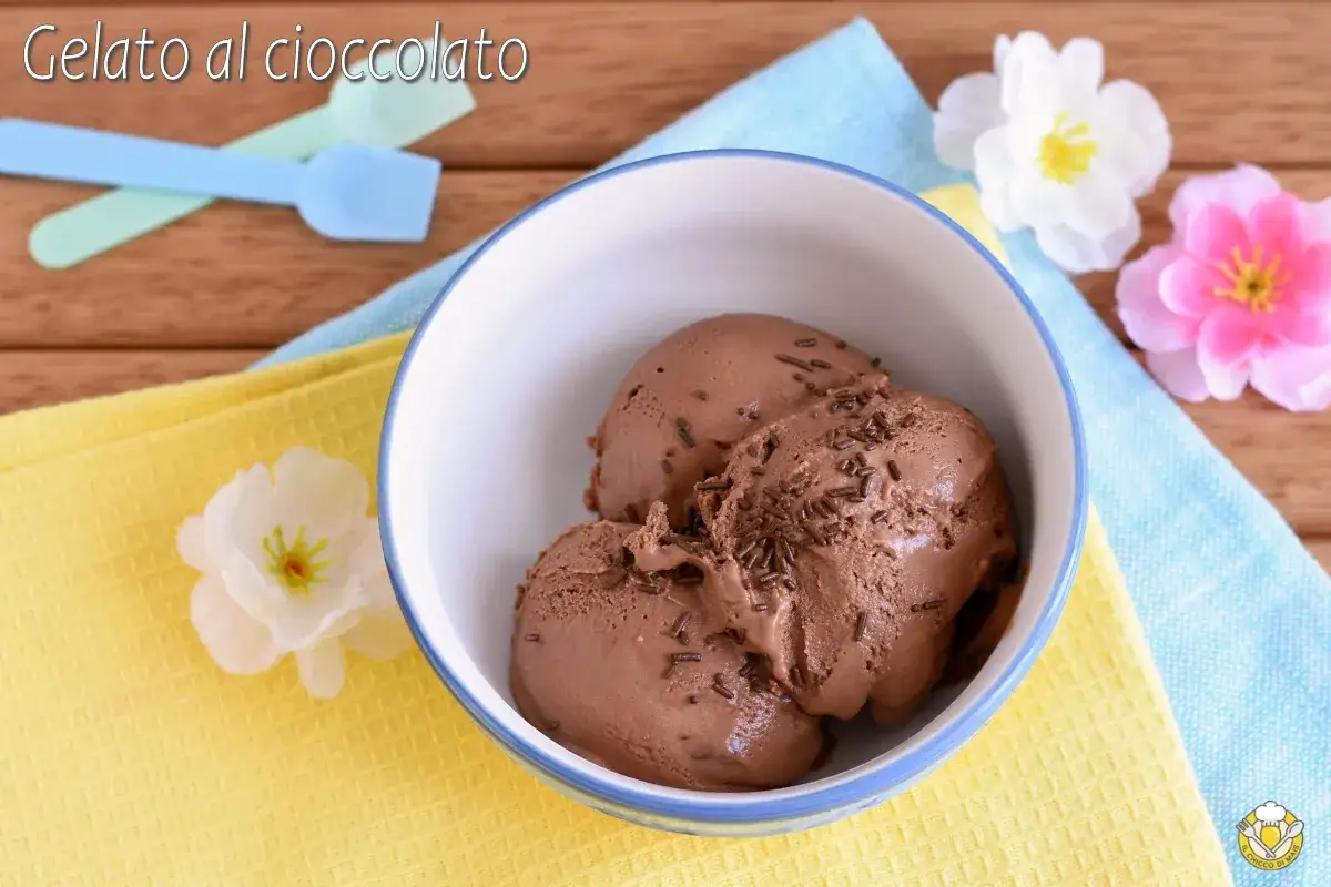 Tre palline di cremoso gelato al cioccolato con granella, servite in una ciotola bianca con bordo blu.
