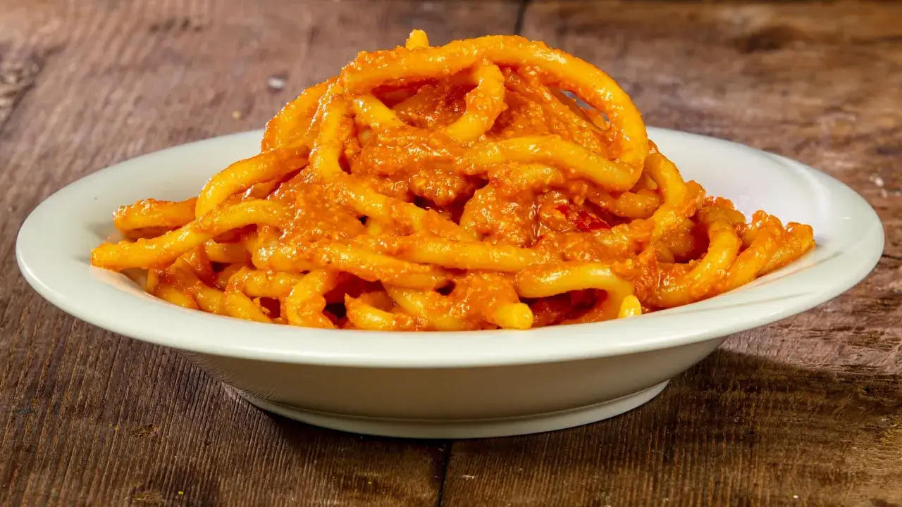 Un piatto di pici all'aglione, pasta fatta a mano condita con un sugo denso e saporito.