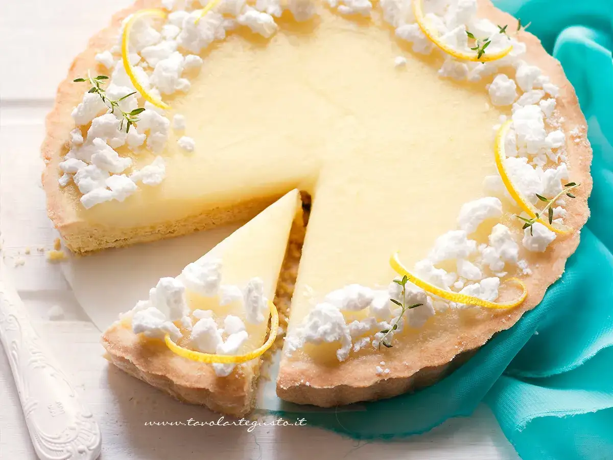 Deliziosa crostata al limone con meringhe e scorzette, una fetta &egrave; gi&agrave; stata servita.