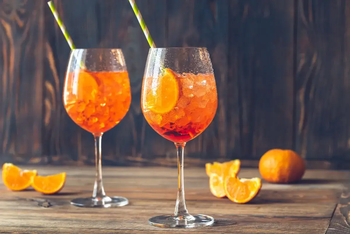 Due calici di Spritz, con fette d'arancia e cannucce, pronti per essere gustati. La soda o tonica per spritz dona la giusta effervescenza.