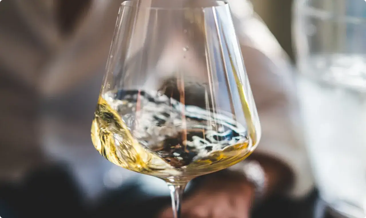 Calice di vino bianco, con riflessi dorati, ideale per scoprire i migliori ribolla gialla abbinamenti con pesce e crostacei.
