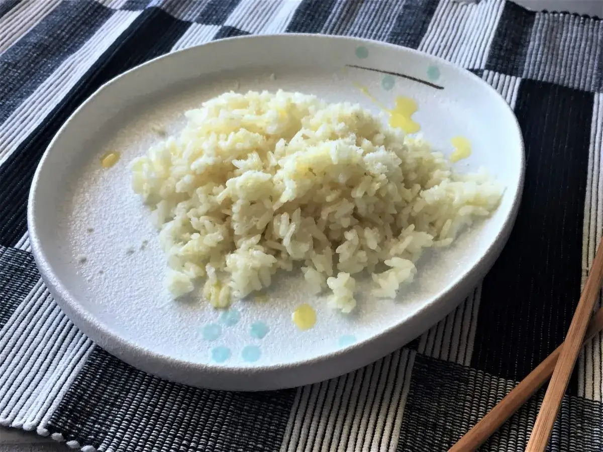Un piatto di riso bianco cotto a puntino, pronto per essere gustato. Ecco come cuocere il riso per un risultato perfetto.