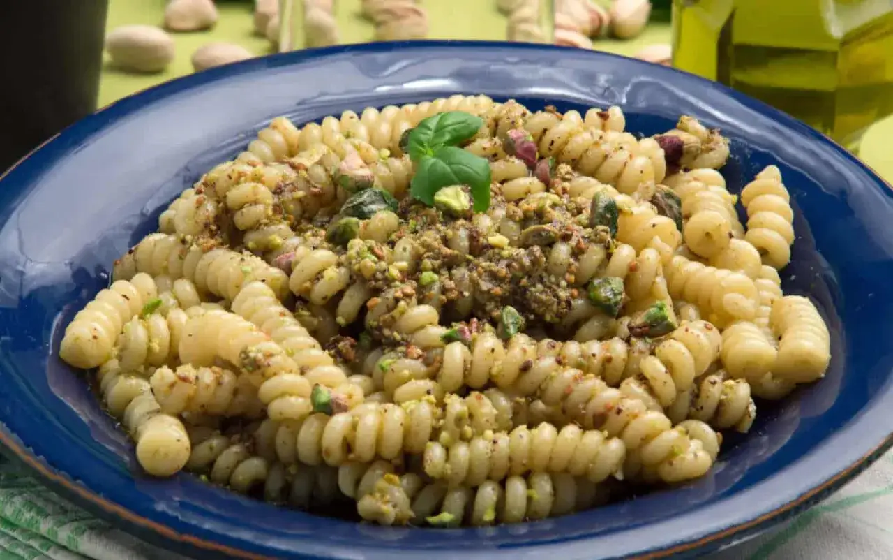 Fusilli conditi con un saporito pesto di pistacchi, guarniti con pistacchi tritati e una fogliolina di basilico.