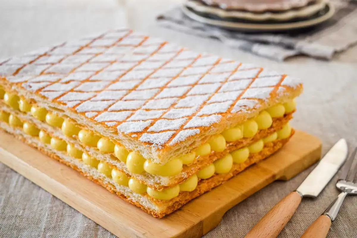 Una deliziosa torta millefoglie con strati di pasta sfoglia e crema pasticcera, cosparsa di zucchero a velo.