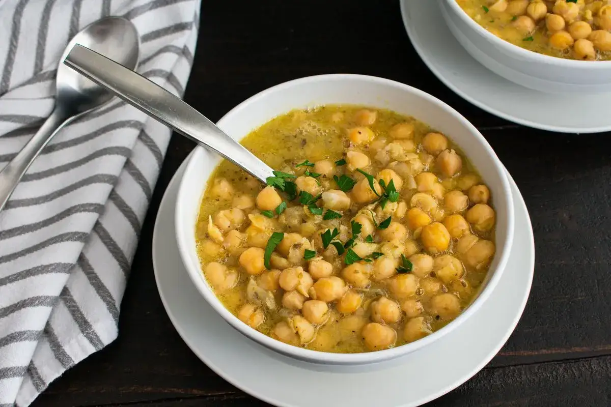 Una ciotola fumante di zuppa di ceci, guarnita con prezzemolo fresco, pronta per essere gustata.