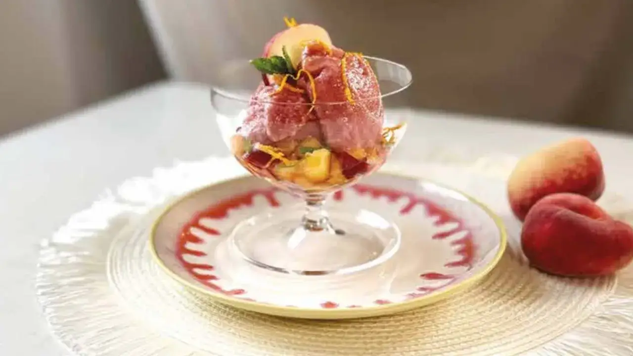 Coppa di gelato al vino con pesche e scorza d'arancia, un dessert estivo rinfrescante.
