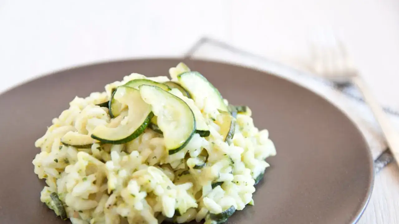 Un cremoso risotto con zucchine, guarnito con fette di zucchine fresche. Un piatto leggero e gustoso.