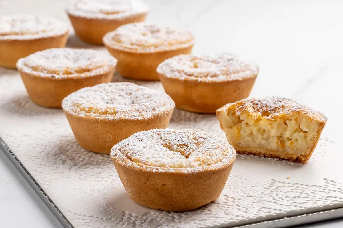 Deliziosi pasticcini con un ripieno cremoso che ricorda il budino di riso, cosparsi di zucchero a velo.