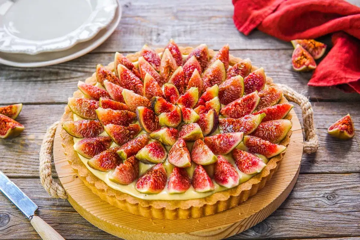 Una deliziosa crostata di fichi, con la sua base dorata e il ripieno cremoso, decorata con fette succose di fichi freschi.