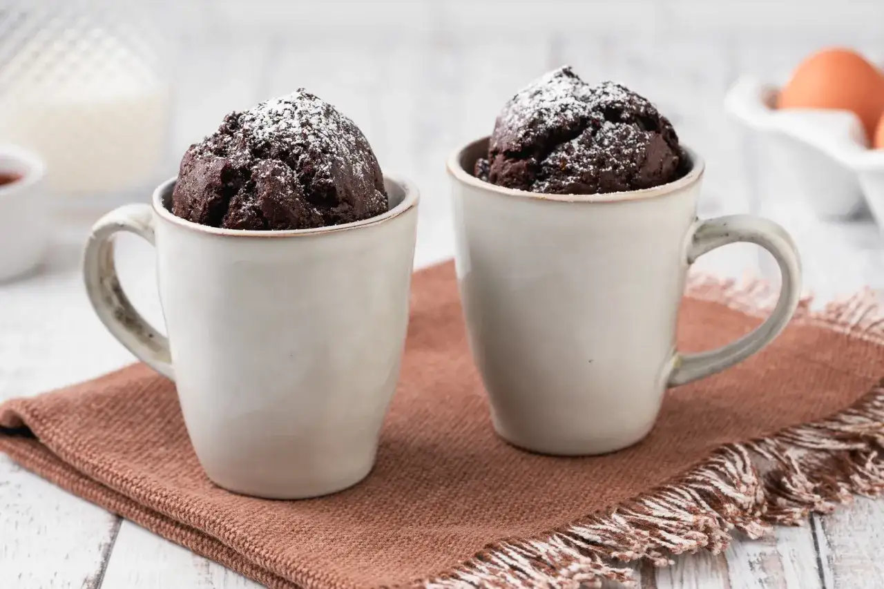 Due deliziose torta in tazza al cioccolato, spolverate di zucchero a velo, pronte per essere gustate.