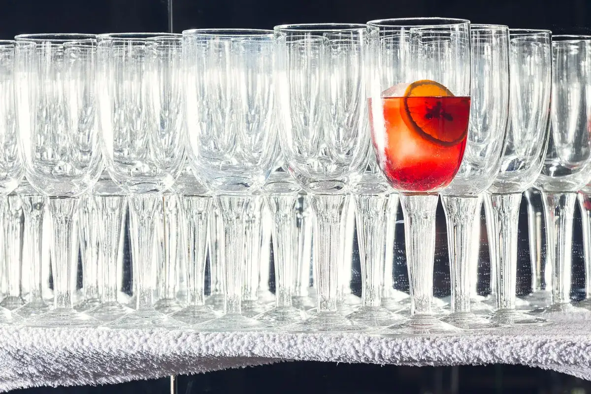 Un bicchiere di Negroni Sbagliato, con la sua storia, spicca tra tanti bicchieri vuoti.