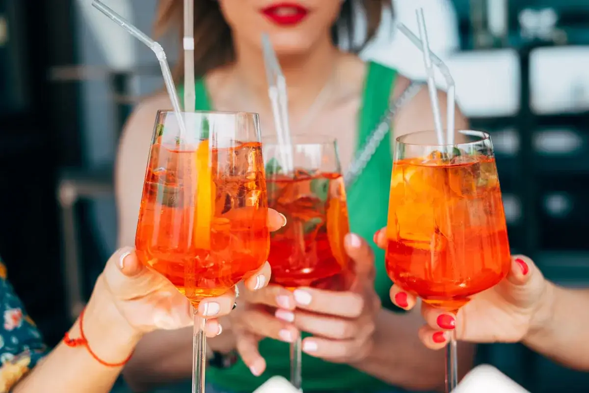 Tre bicchieri di Spritz, con ghiaccio e arancia, pronti per essere gustati. Il grado alcolico spritz &egrave; perfetto per un aperitivo rinfrescante.