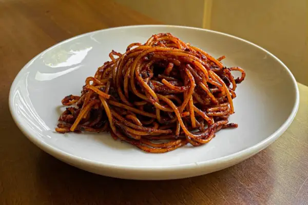 Un piatto di spaghetti all'assassina, conditi con un sugo rosso piccante e saporito, pronti per essere gustati.